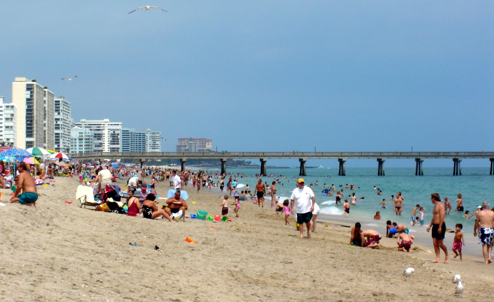 Beachgoers beside the Deerfield Beach International Fishing Pier in Deerfield Beach, Florida